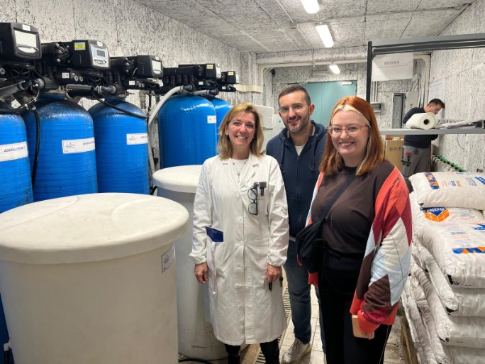 A group of people standing in a room with large white containers
AI-generated content may be incorrect.